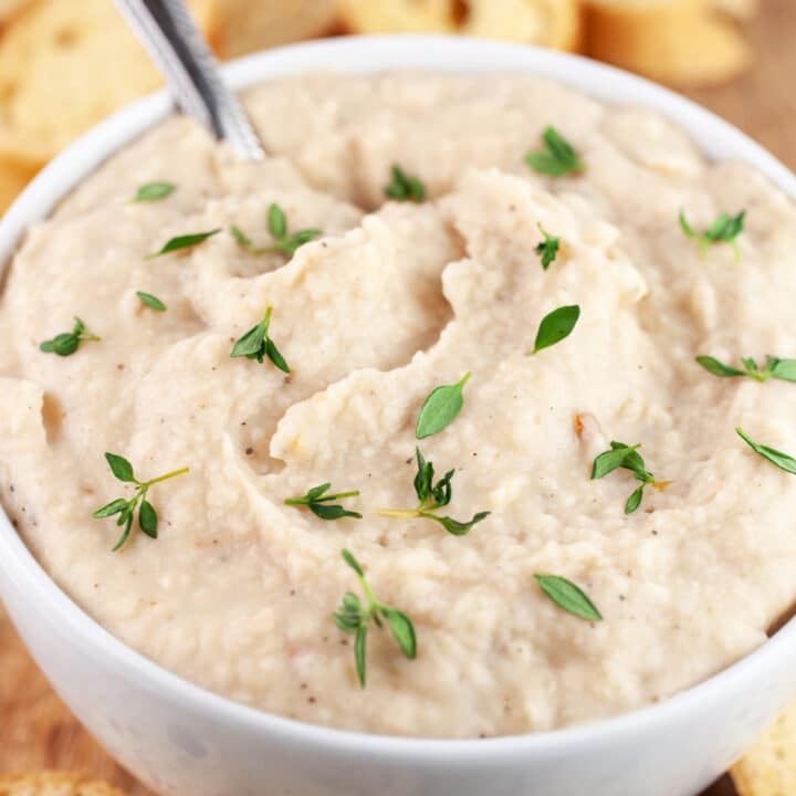 Italian white bean dip in white bowl garnished with fresh thyme.