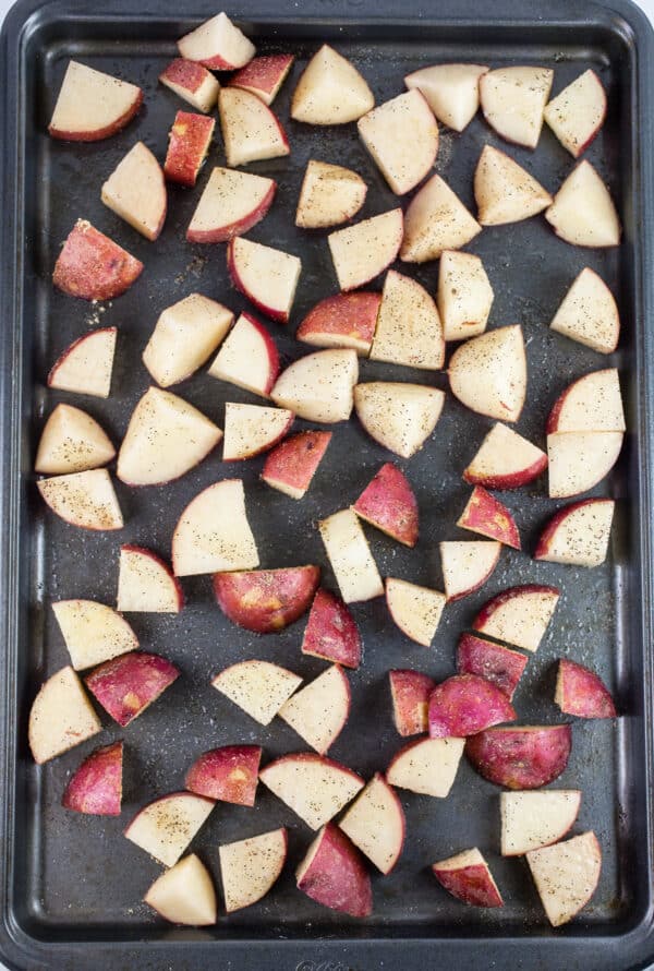 Uncooked diced red potatoes on baking sheet.