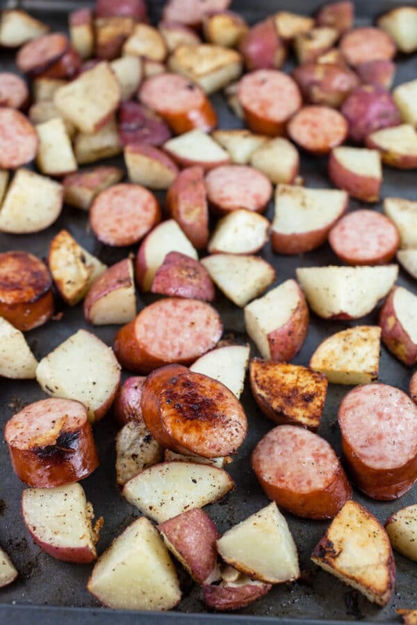 Roasted sausage and potatoes on baking sheet.