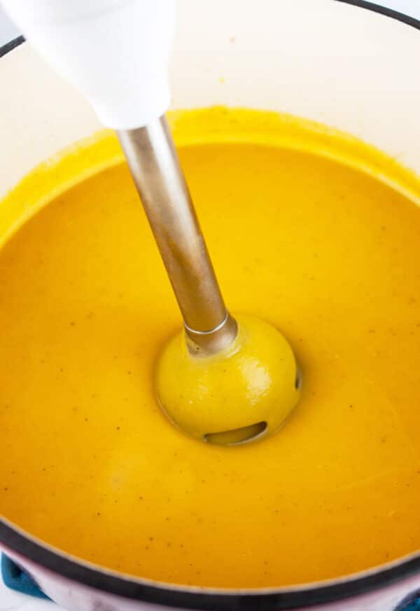Butternut squash soup in Dutch oven pureed with an immersion blender.