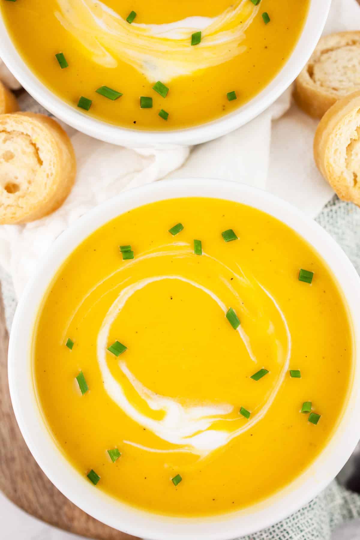 Butternut squash soup in white bowls next to toasted crostini.