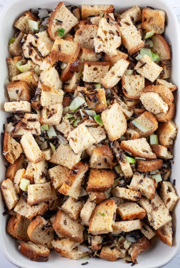 Toasted bread cubes, cooked wild rice, and egg mixture in casserole dish.