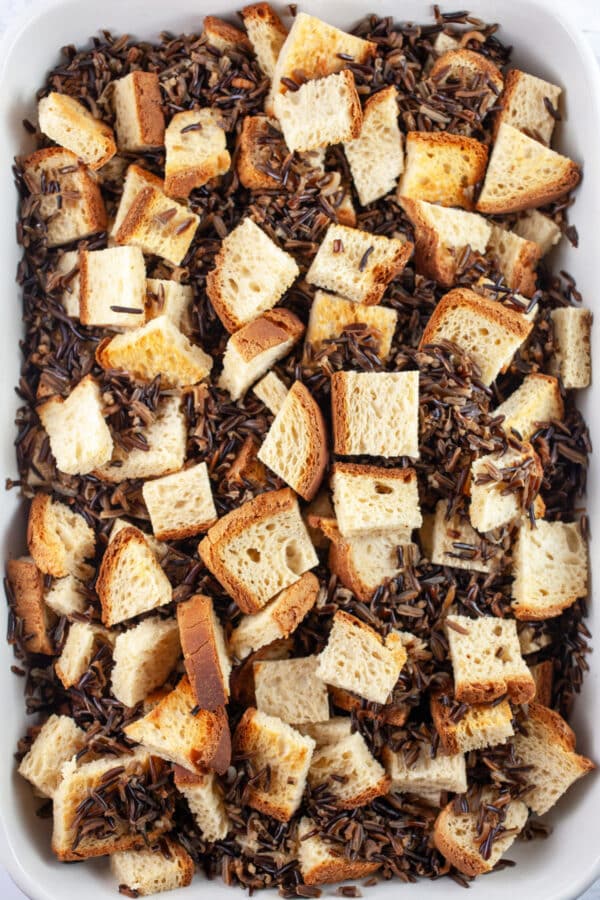 Toasted bread cubes and cooked wild rice in casserole dish.