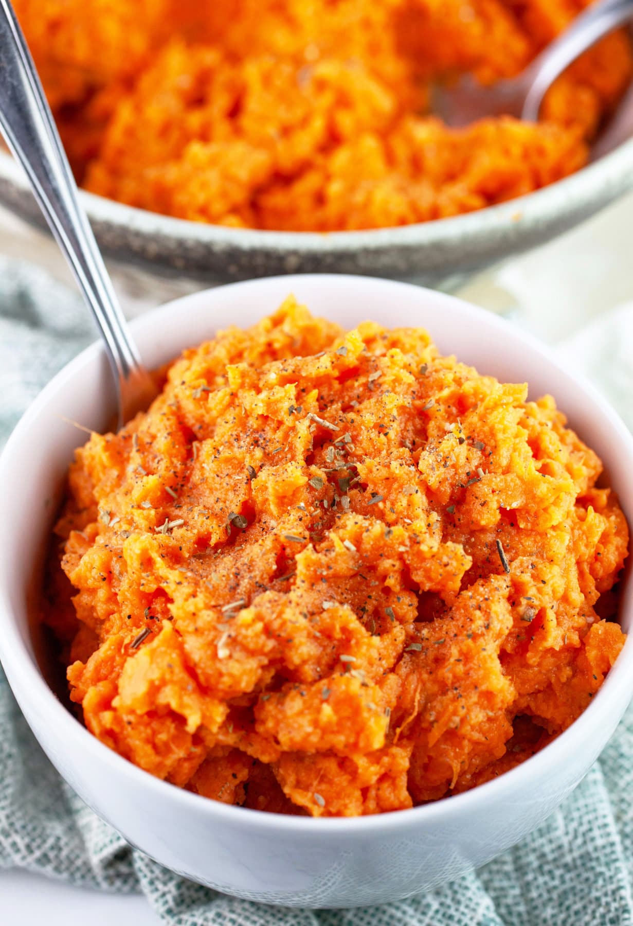 Savory mashed sweet potatoes in bowl with fork and spoon.