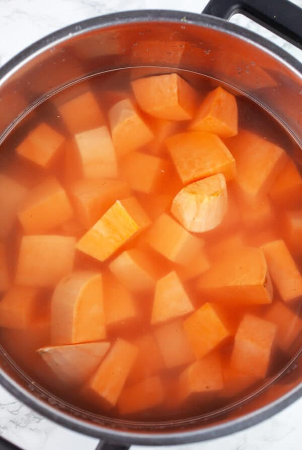 Uncooked diced sweet potatoes in pot of water.