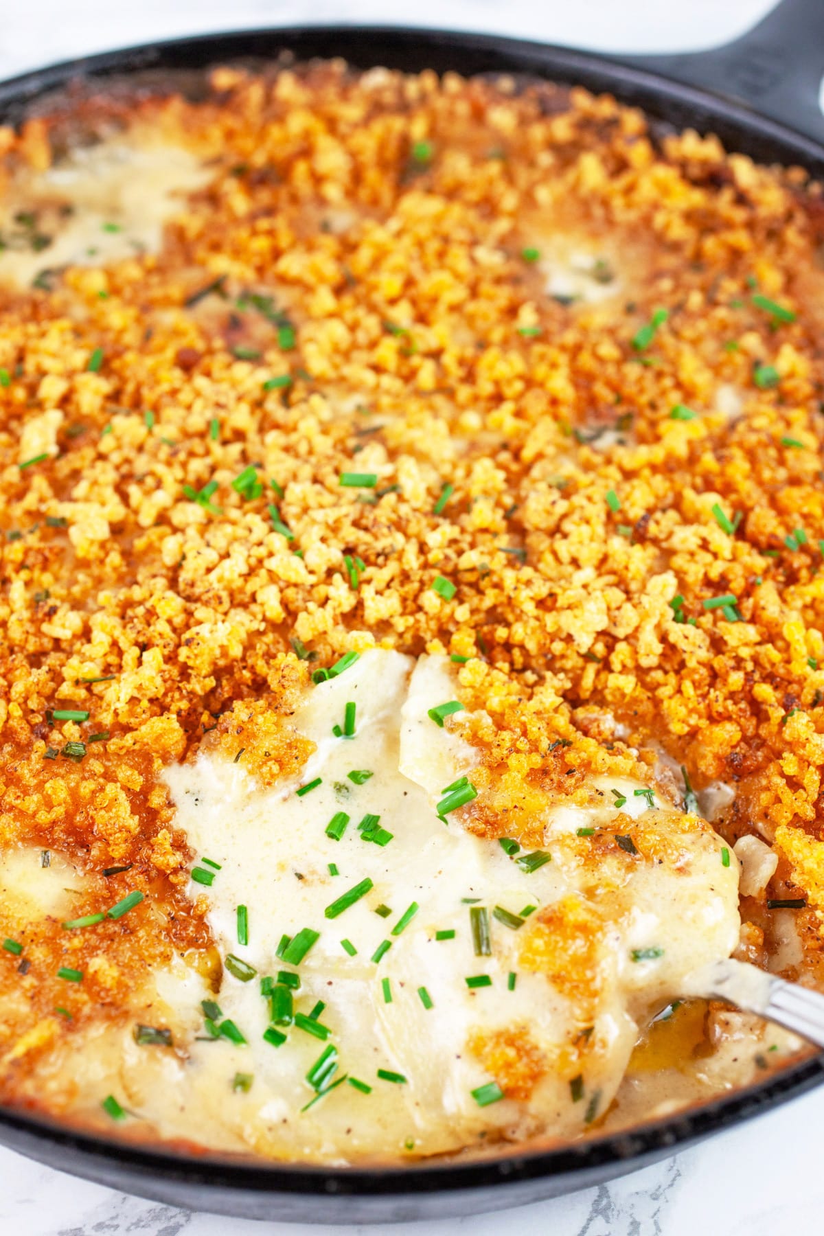 Baked kohlrabi gratin in cast iron skillet with serving spoon.