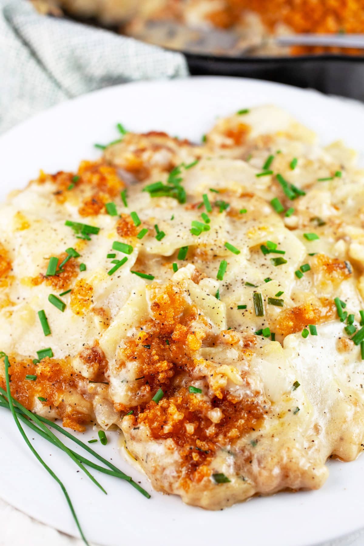 Kohlrabi gratin on white plate garnished with fresh chives.