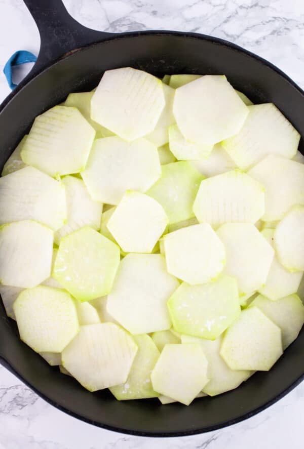 Raw sliced kohlrabi in cast iron skillet.