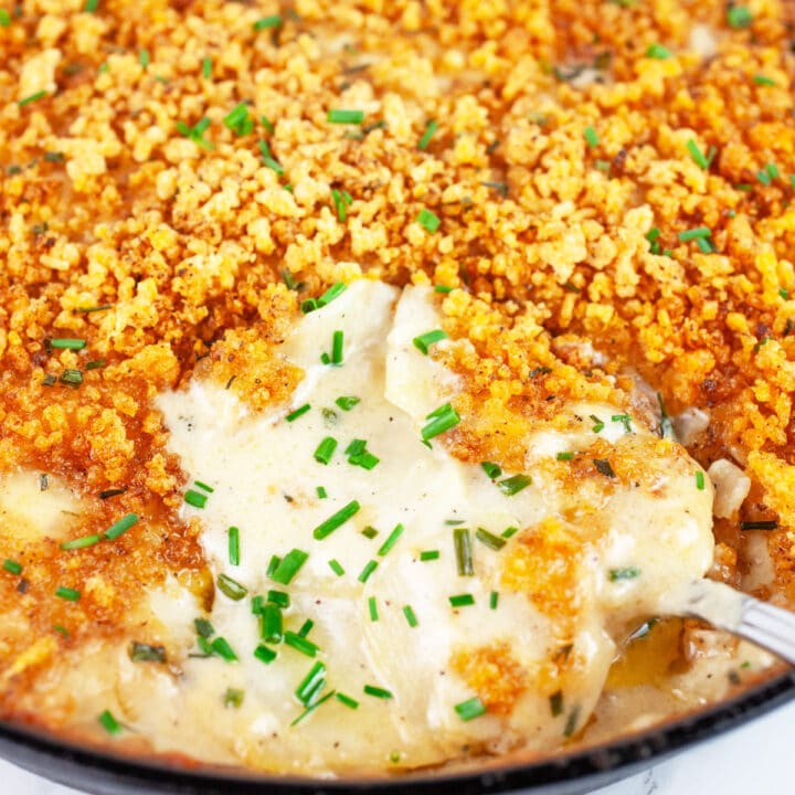 Kohlrabi gratin in cast iron skillet with serving spoon.