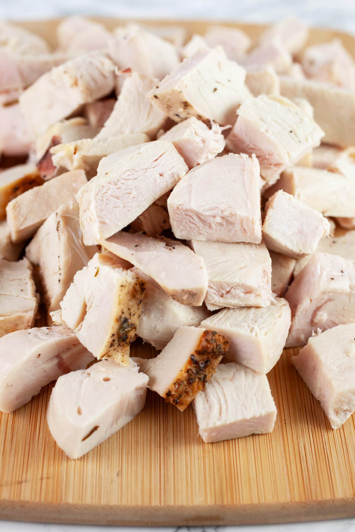 Chopped cooked turkey on wooden cutting board.