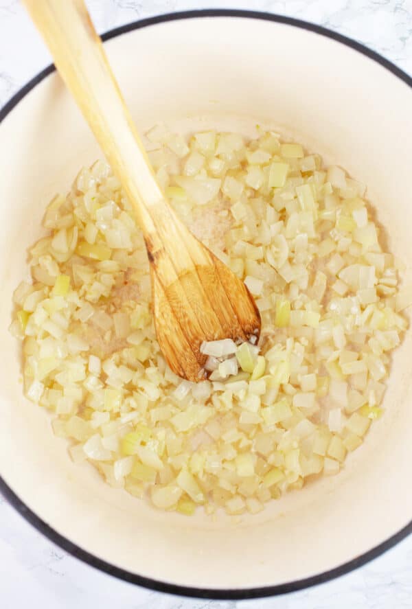 Minced garlic and onions sauteed in Dutch oven with wooden spoon.