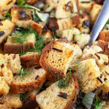 Wild rice fennel stuffing in casserole dish with metal spoon.