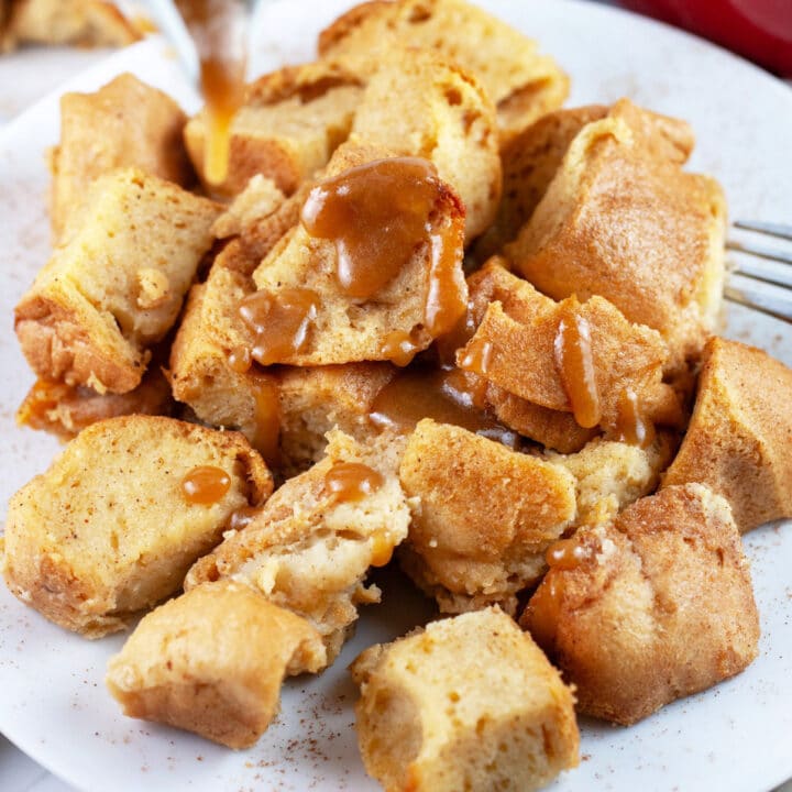 Buttermilk bread pudding with caramel sauce on white plate with fork.