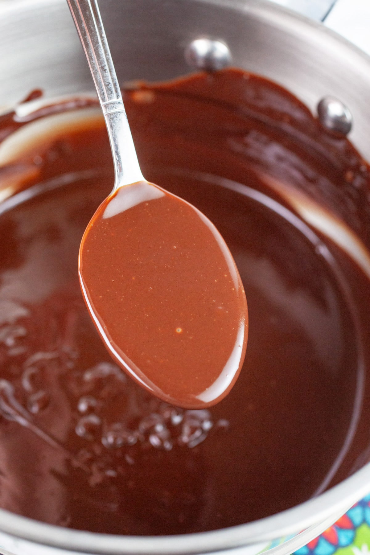 Spoonful of chocolate ganache lifted from sauce pan.