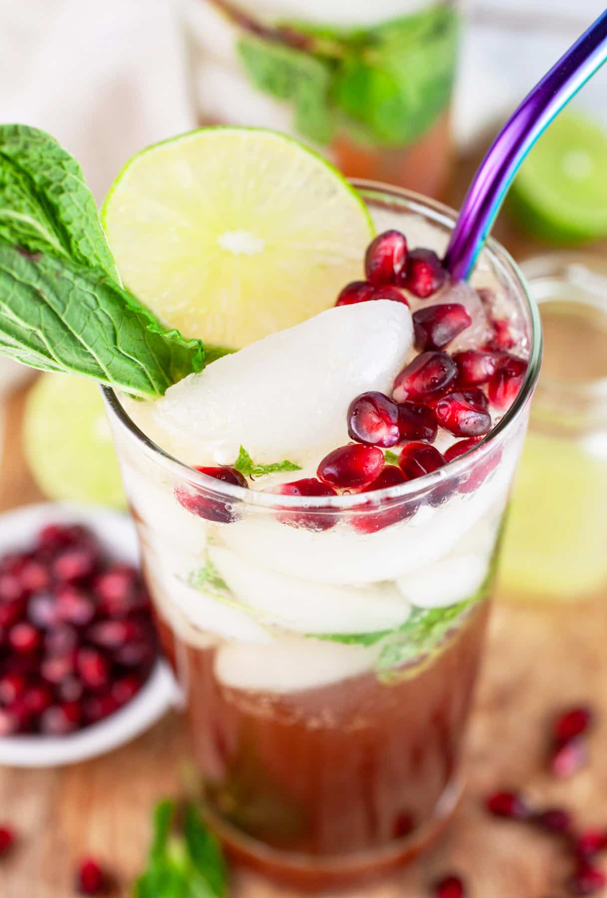 Pomegranate mojito cocktail garnished with fresh mint, lime wheel, and pomegranate seeds.