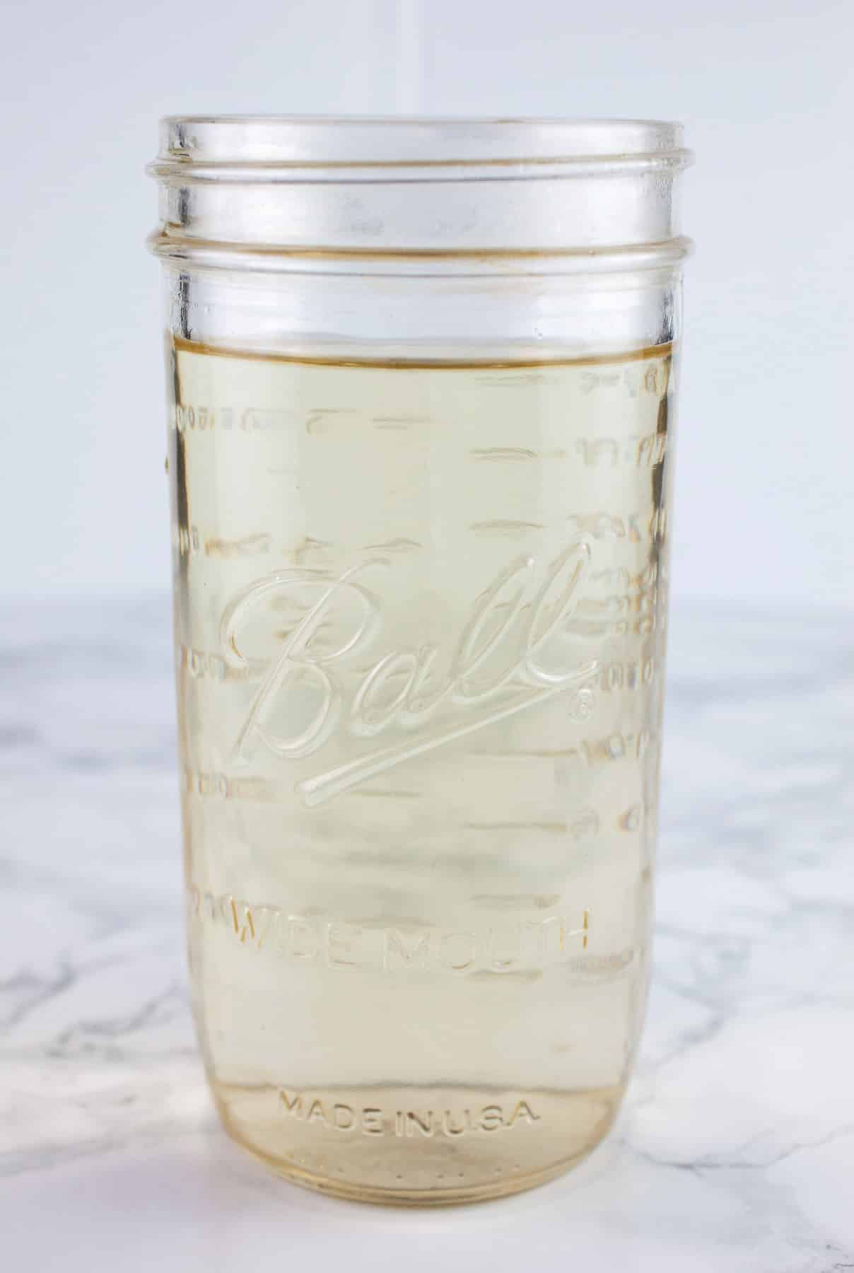 Simple syrup in tall mason jar.
