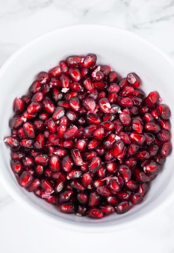 Pomegranate seeds in white bowl.