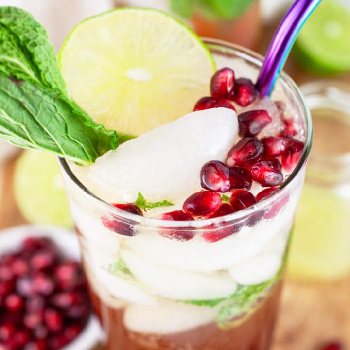 Pomegranate mojito cocktail garnished with fresh mint, lime wheel, and pomegranate seeds.