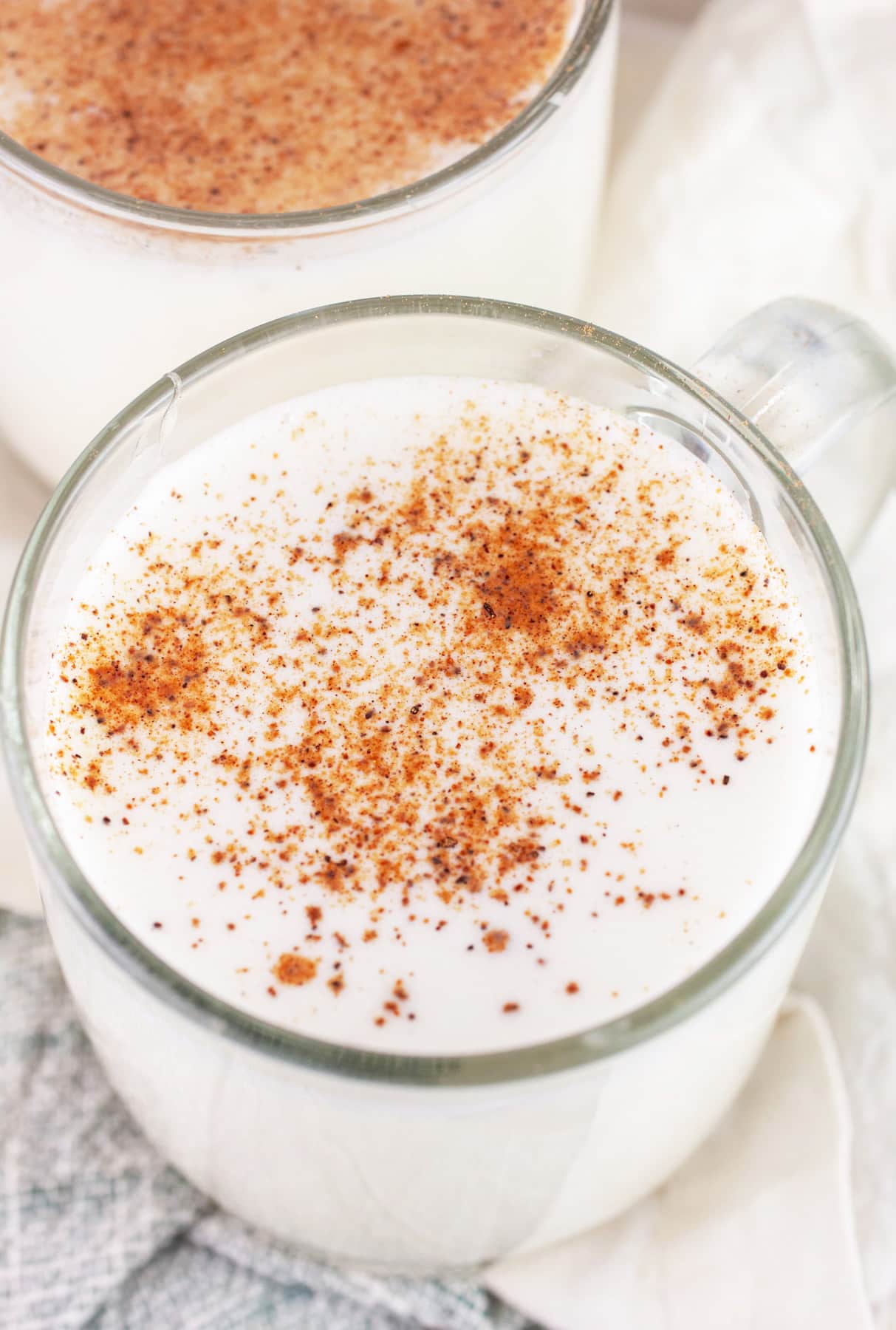 Tom and Jerry drink in glass coffee mug garnished with nutmeg.