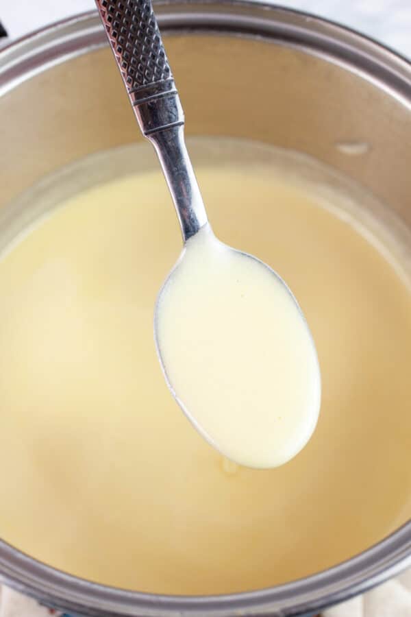 Spoonful of cooked Tom and Jerry batter lifted from sauce pan.