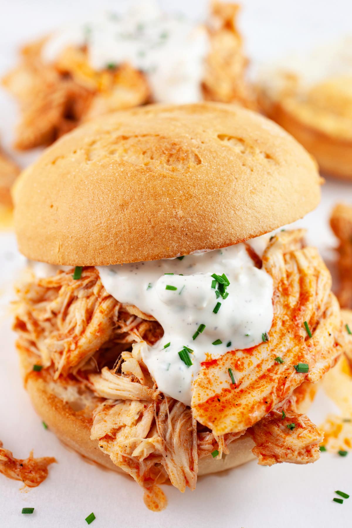 Shredded buffalo chicken sandwiches on toasted buns with blue cheese sauce.