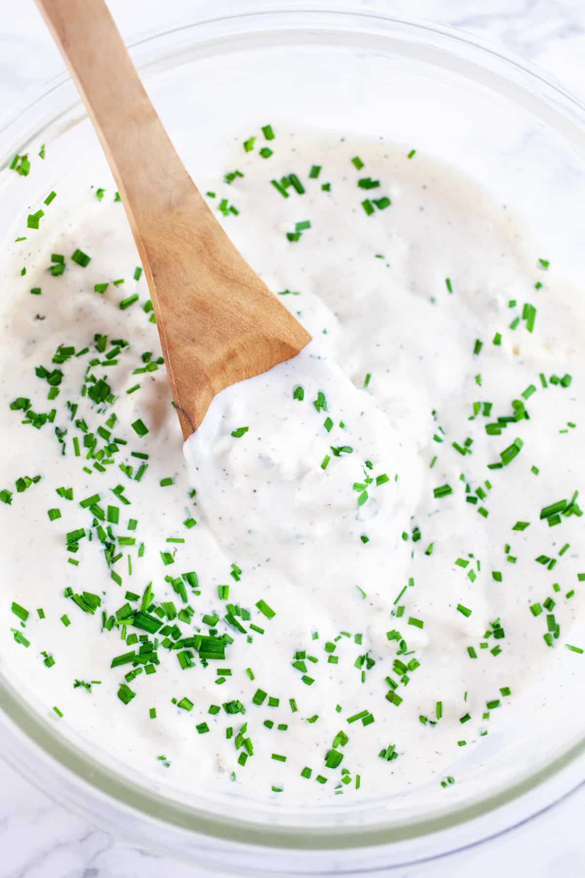 Blue cheese sauce in glass bowl with wooden spoon.