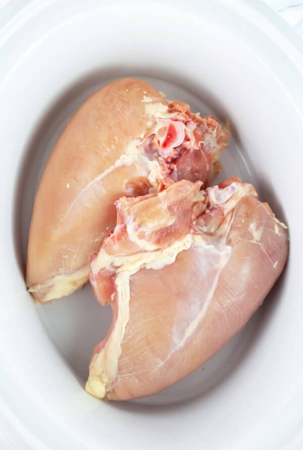 Raw split chicken breasts in slow cooker.