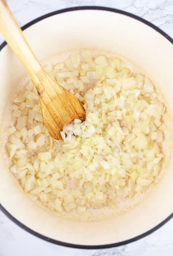 Minced garlic and onions sauteed in Dutch oven with wooden spoon.