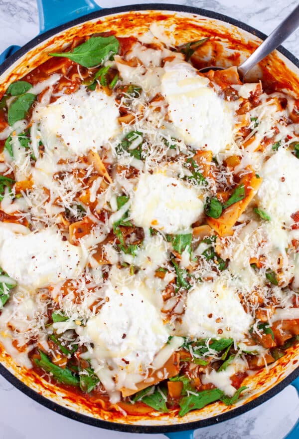Skillet vegetable lasagna with metal spoon.