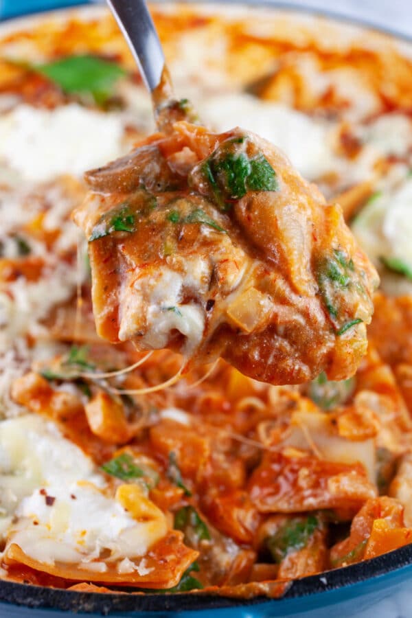 Spoonful of vegetarian lasagna lifted from skillet.