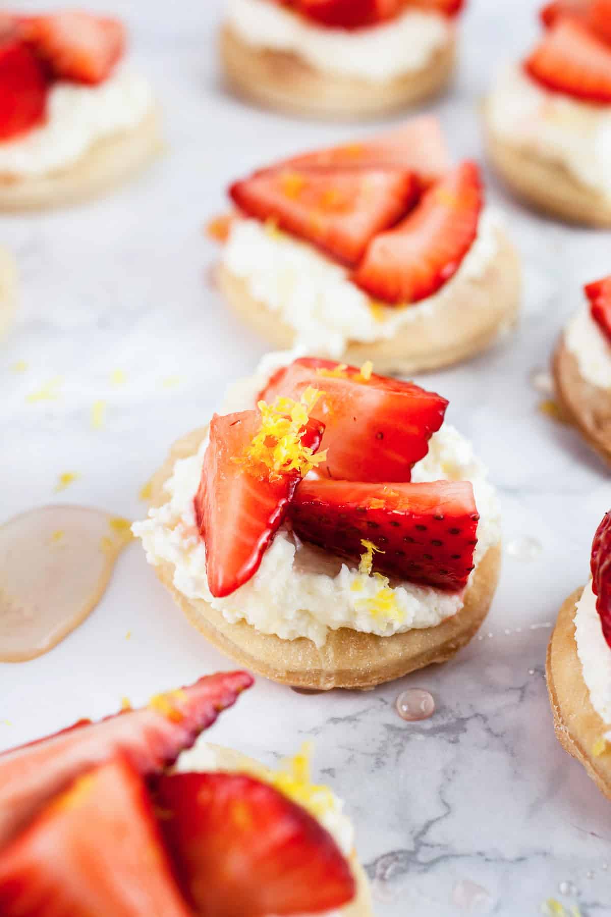 These Honeyed Strawberry and Mascarpone Tartlets make the perfect quick dessert! They're made with light and airy Puff Pastry and topped with a smooth mascarpone cream and fresh strawberries drizzled with honey. Lemon zest balances out the sweetness. These tartlets are fresh and light but decadent at the same time! #ad #puffpastry #inspiredbypuff Strawberry mascarpone tartlets with honey and lemon zest.