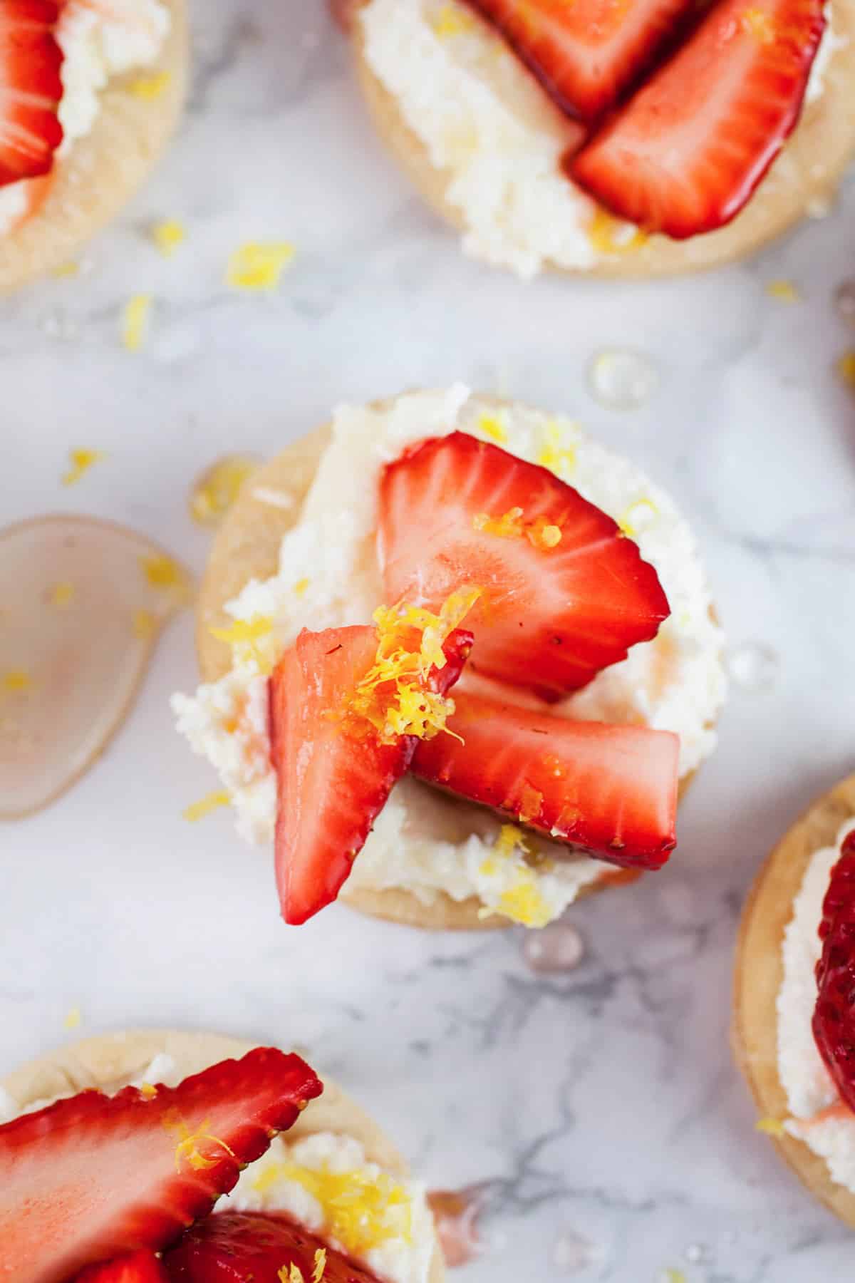 These Honeyed Strawberry and Mascarpone Tartlets make the perfect quick dessert! They're made with light and airy Puff Pastry and topped with a smooth mascarpone cream and fresh strawberries drizzled with honey. Lemon zest balances out the sweetness. These tartlets are fresh and light but decadent at the same time! #ad #puffpastry #inspiredbypuff Strawberry mascarpone tartlets with honey and lemon zest.