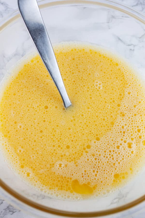 Wet ingredients in glass mixing bowl with fork.