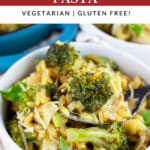 Vegetable pesto pasta with broccoli and span peas garnished with fresh basil in white bowl with fork.