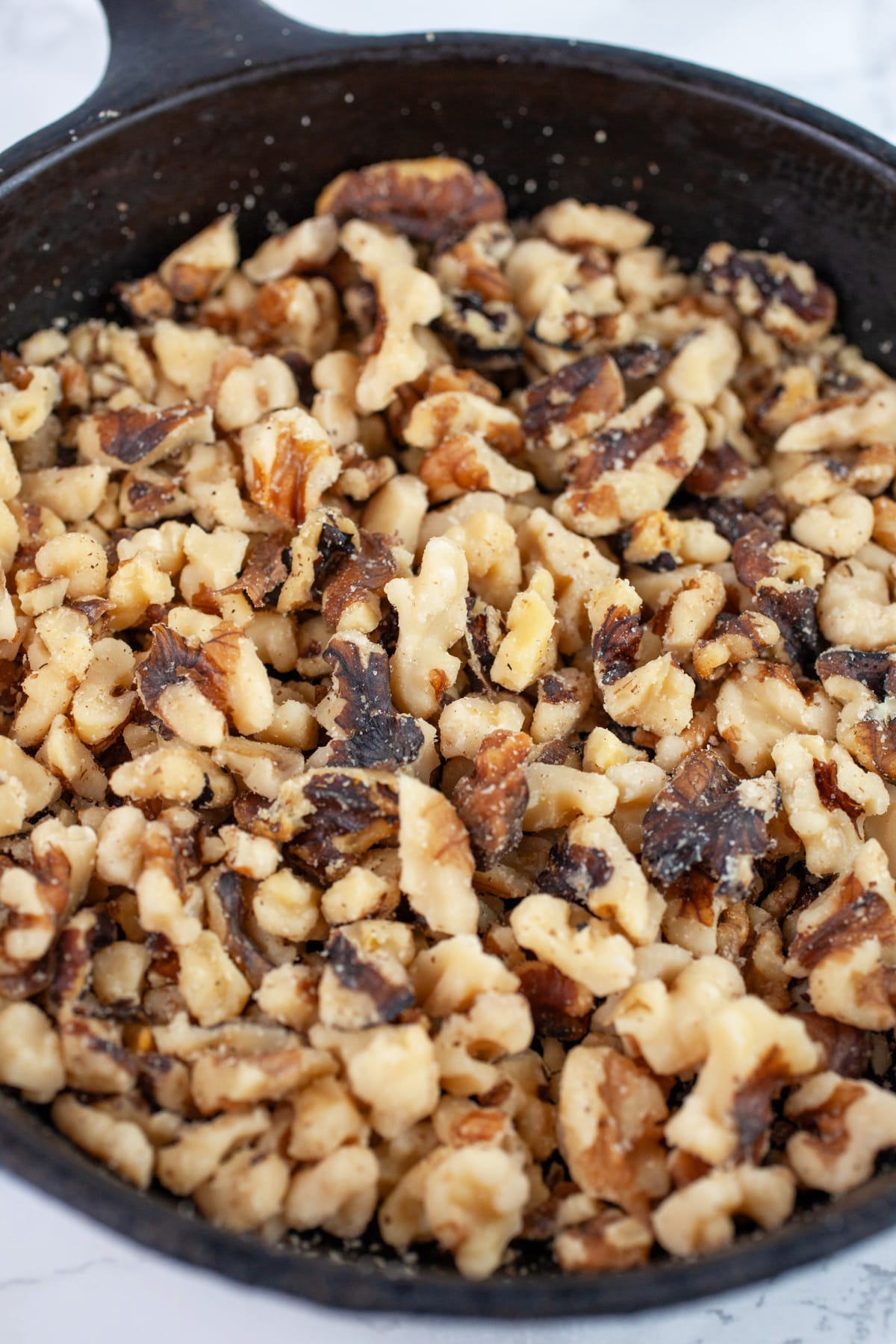 Toasted walnuts in small cast iron skillet.