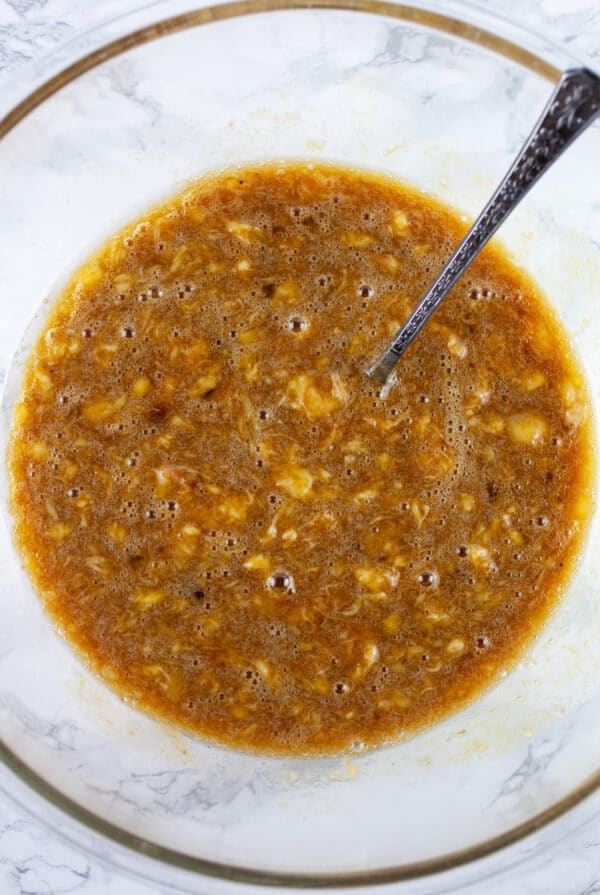 Wet ingredients in glass bowl with fork.