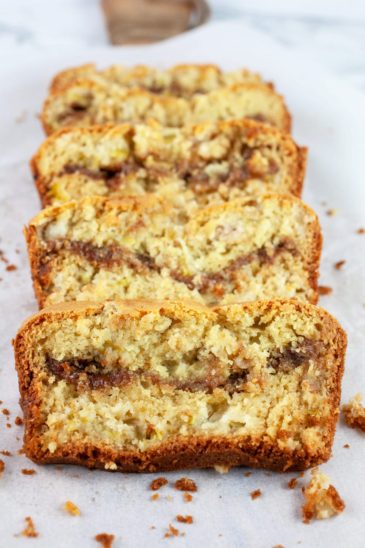 Sliced gluten free rhubarb bread on serving board with parchment paper.