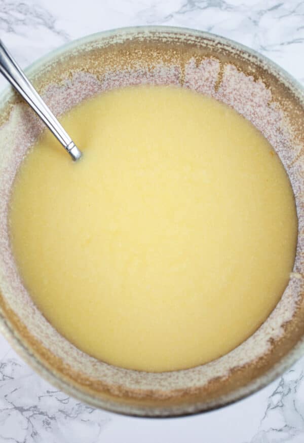 Wet ingredients in ceramic bowl with metal spoon.