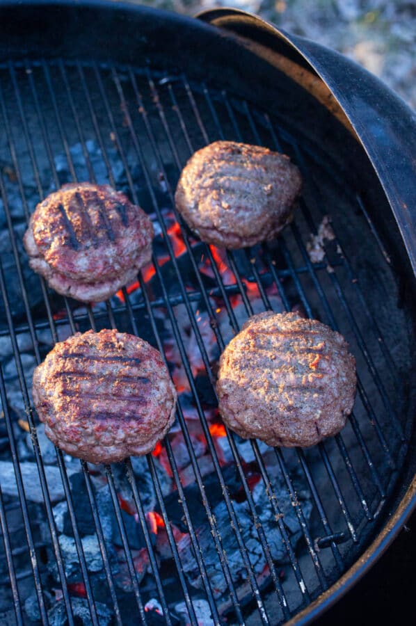 Cooked ground beef burgers on charcoal grill.