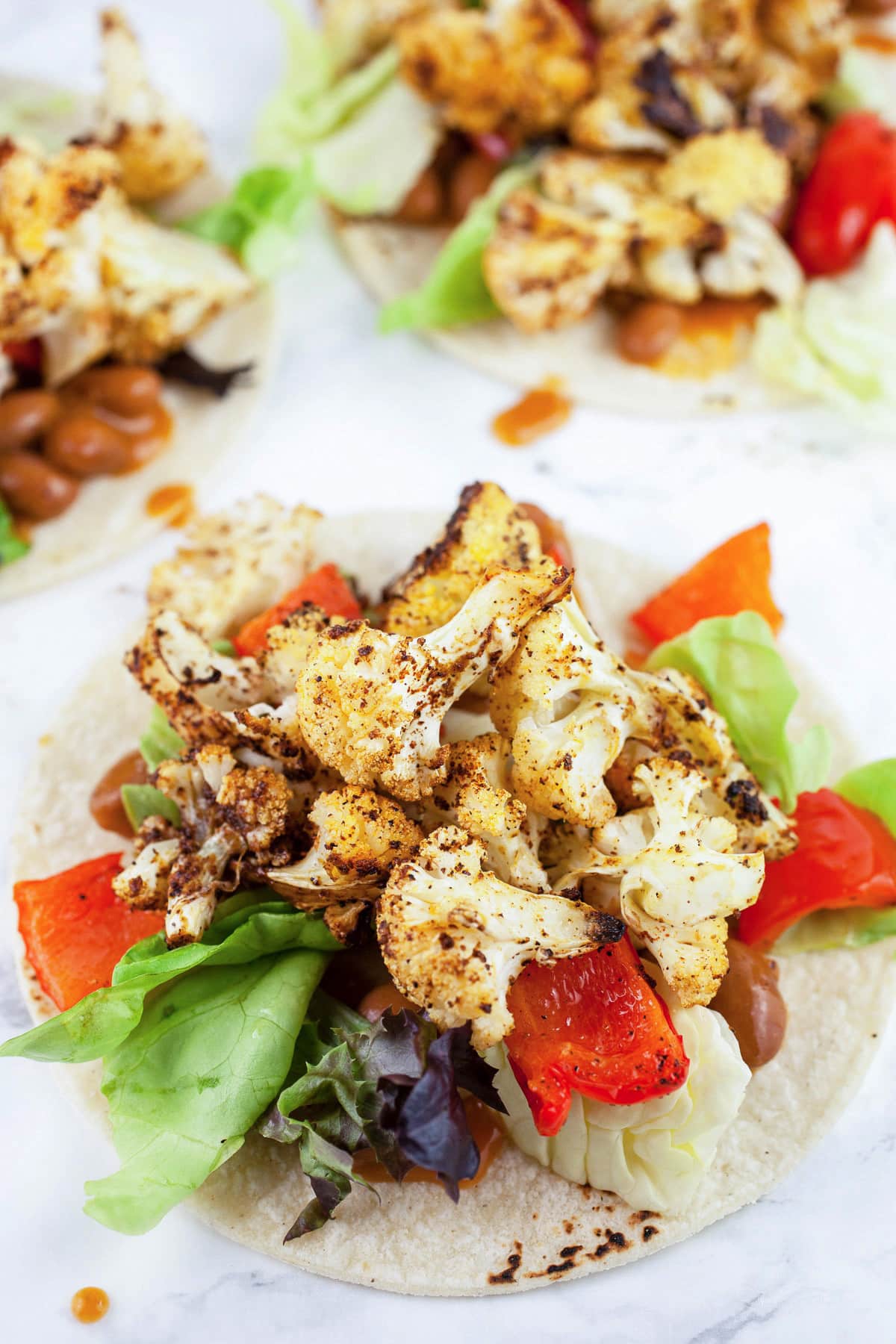Roasted cauliflower and red pepper tacos on corn tortillas.