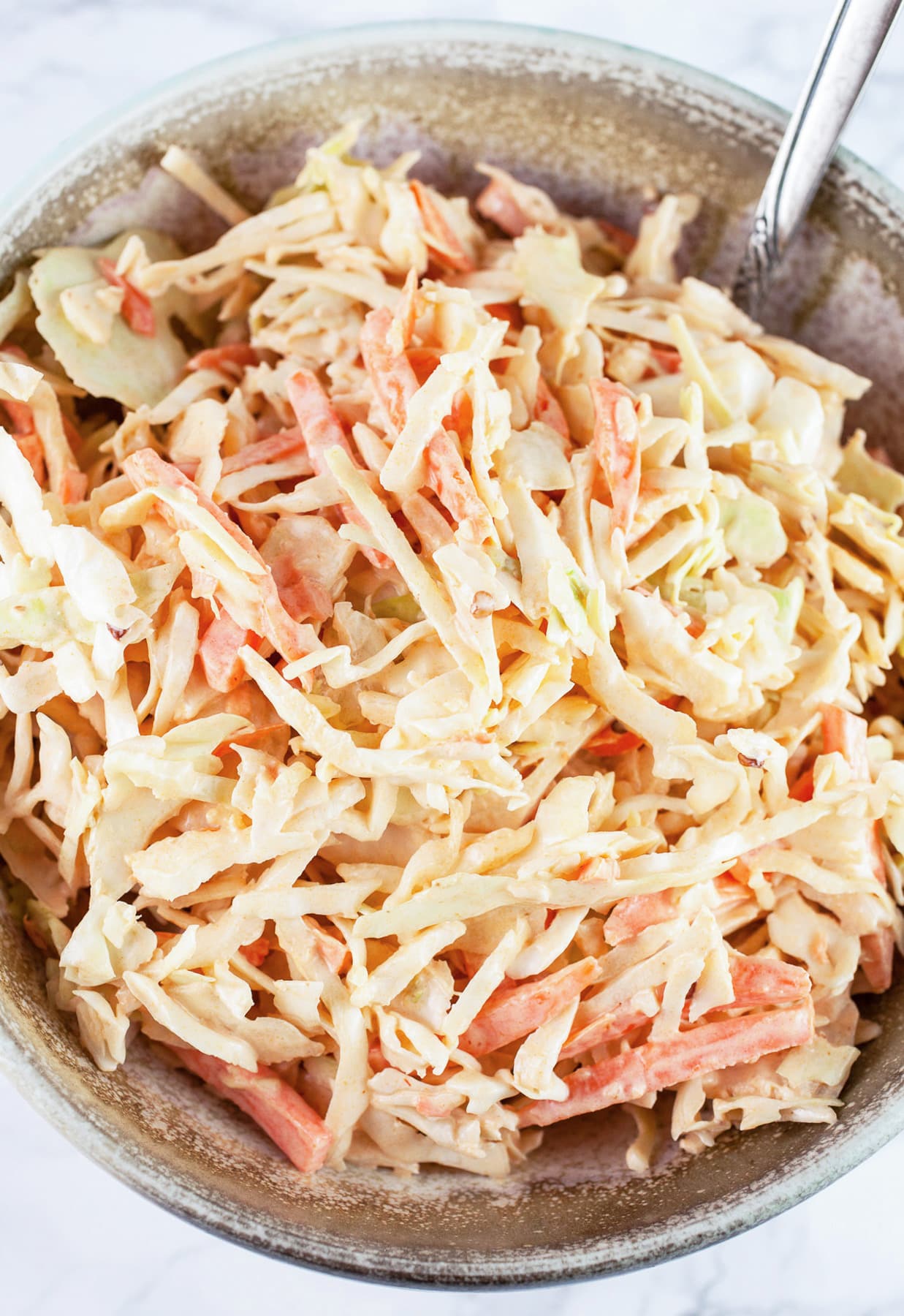 Chipotle coleslaw in ceramic bowl with spoon.