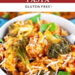 Sausage broccoli pasta garnished with Parmesan cheese and fresh basil in white bowl with fork.