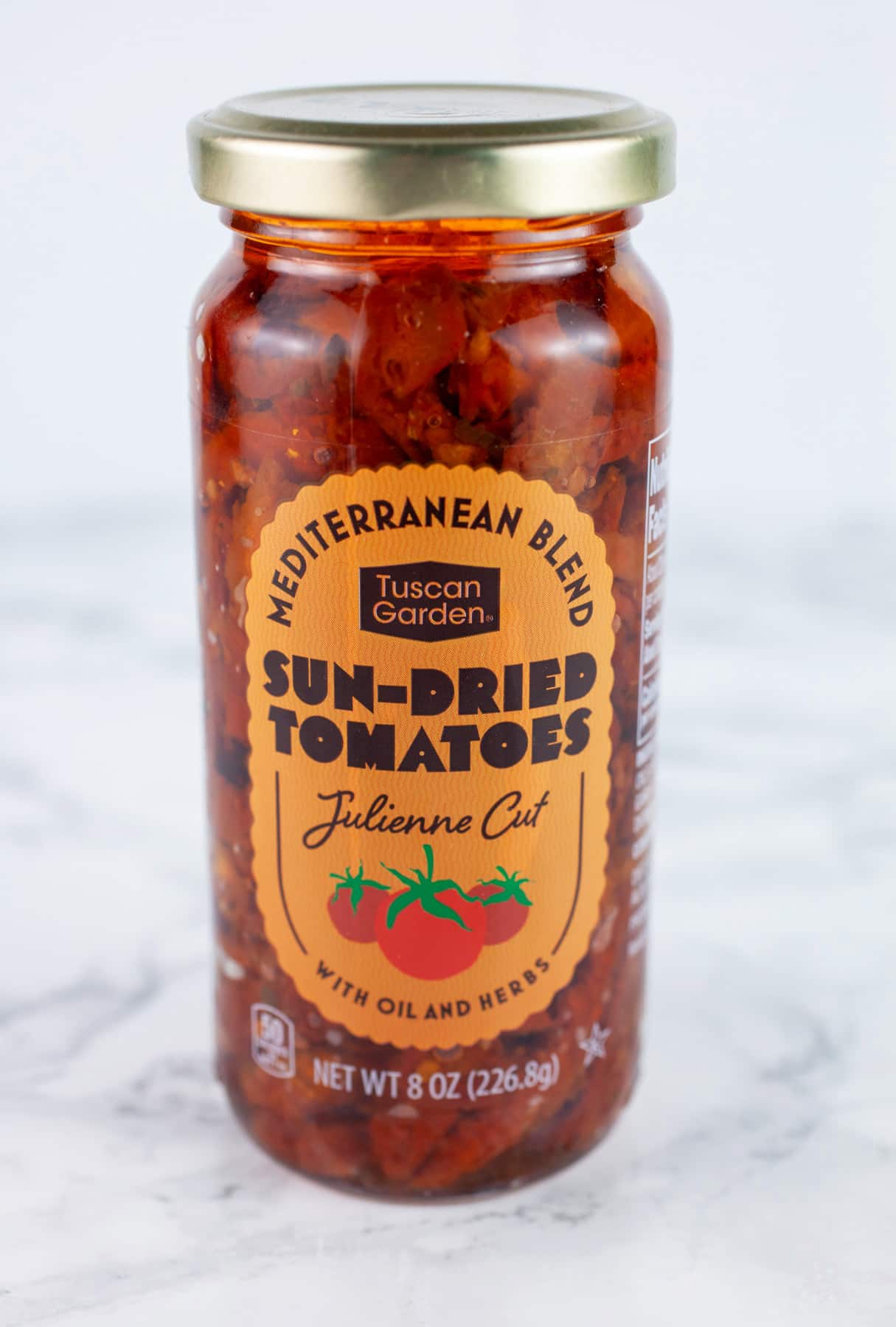 Unopened jar of sun dried tomatoes on white surface.