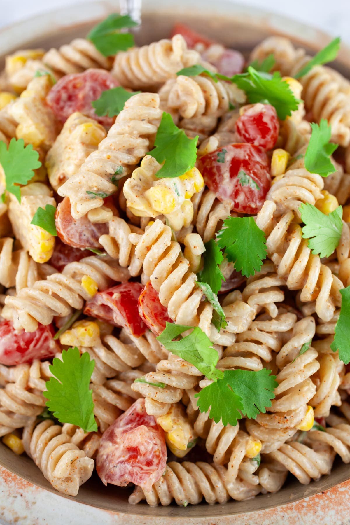 Southwest pasta salad garnished with cilantro in ceramic bowl.