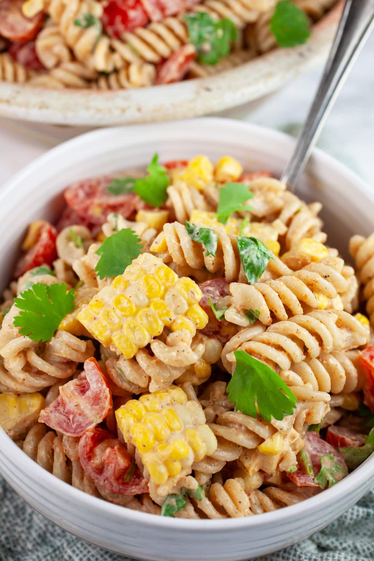 Southwest pasta salad garnished with cilantro in white bowl with fork.