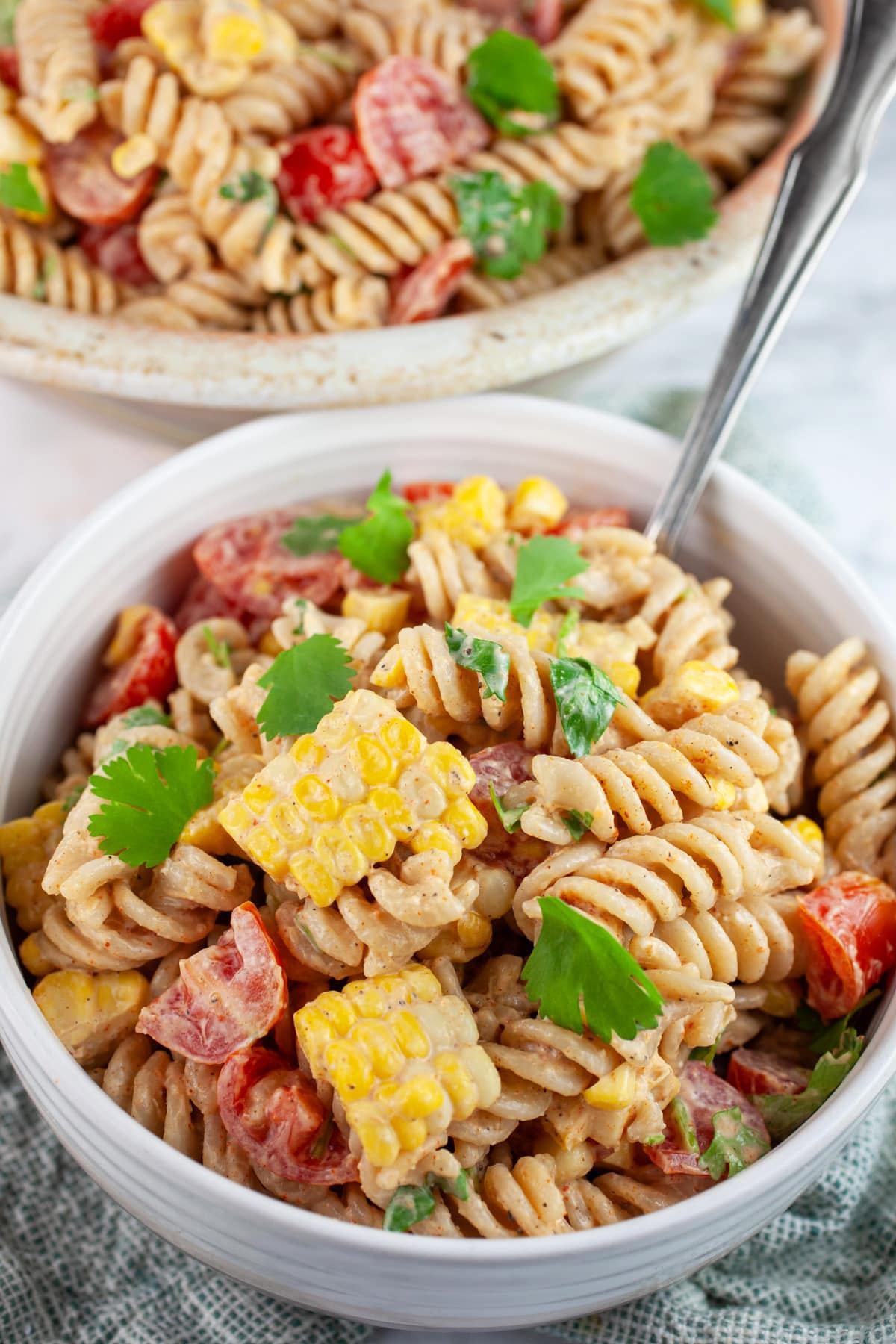 Southwest pasta salad with corn and tomatoes in white bowl with fork.