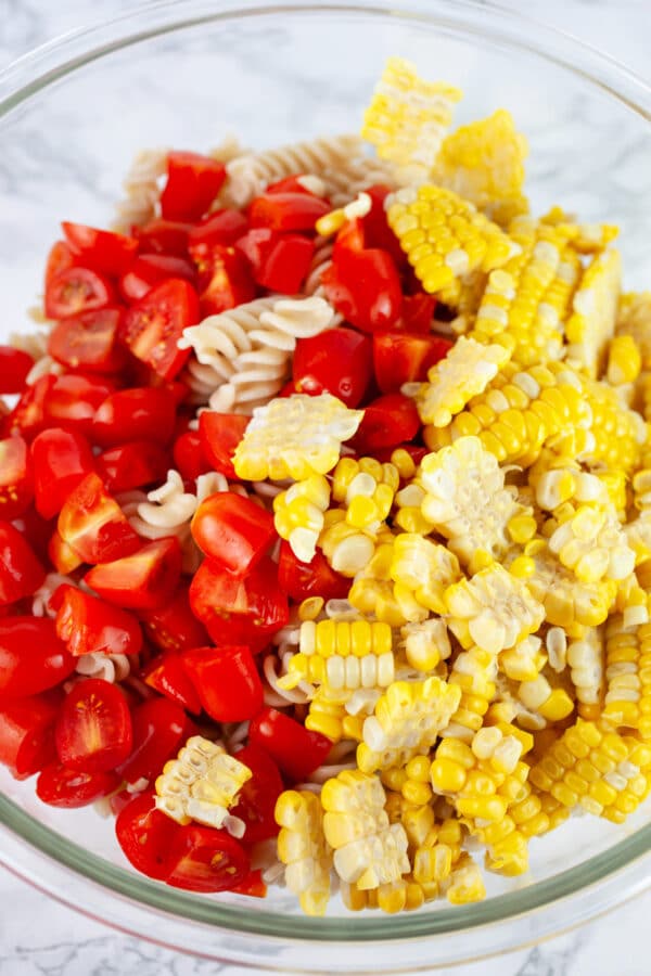 Chopped grape tomatoes and corn added to large mixing bowl.
