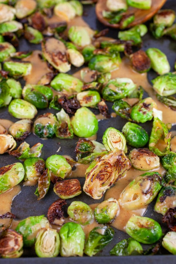 Glaze poured over roasted Brussels sprouts on baking sheet.