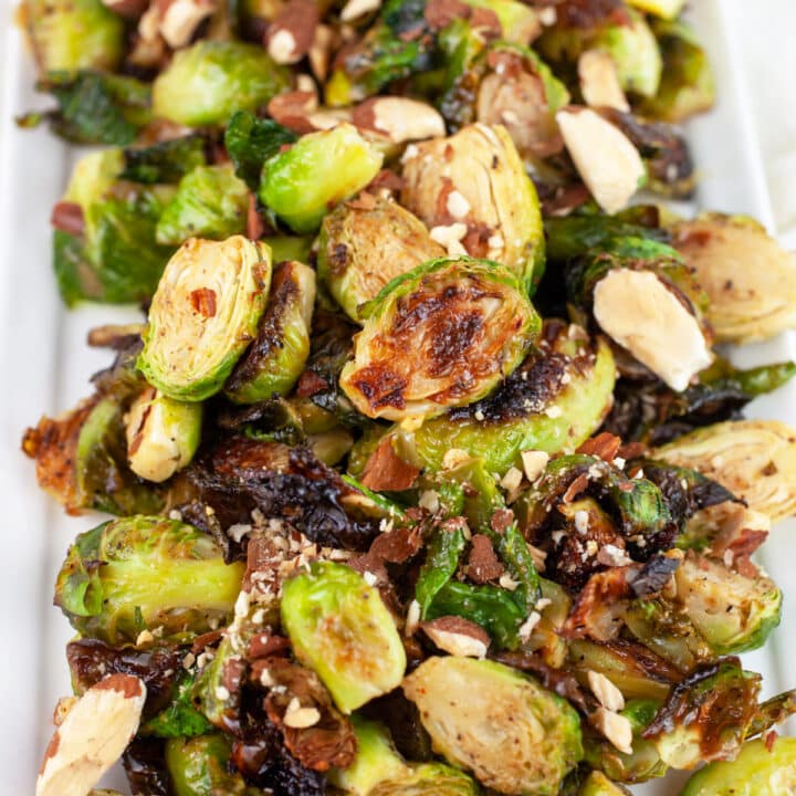 Maple mustard roasted Brussels sprouts on white platter with almonds.