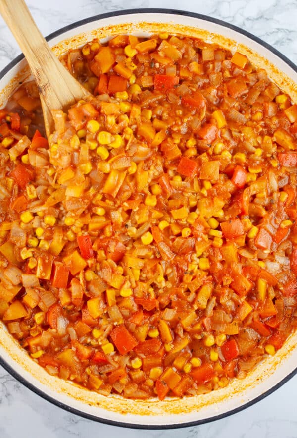 Cooked Mexican rice in Dutch oven with wooden spoon.